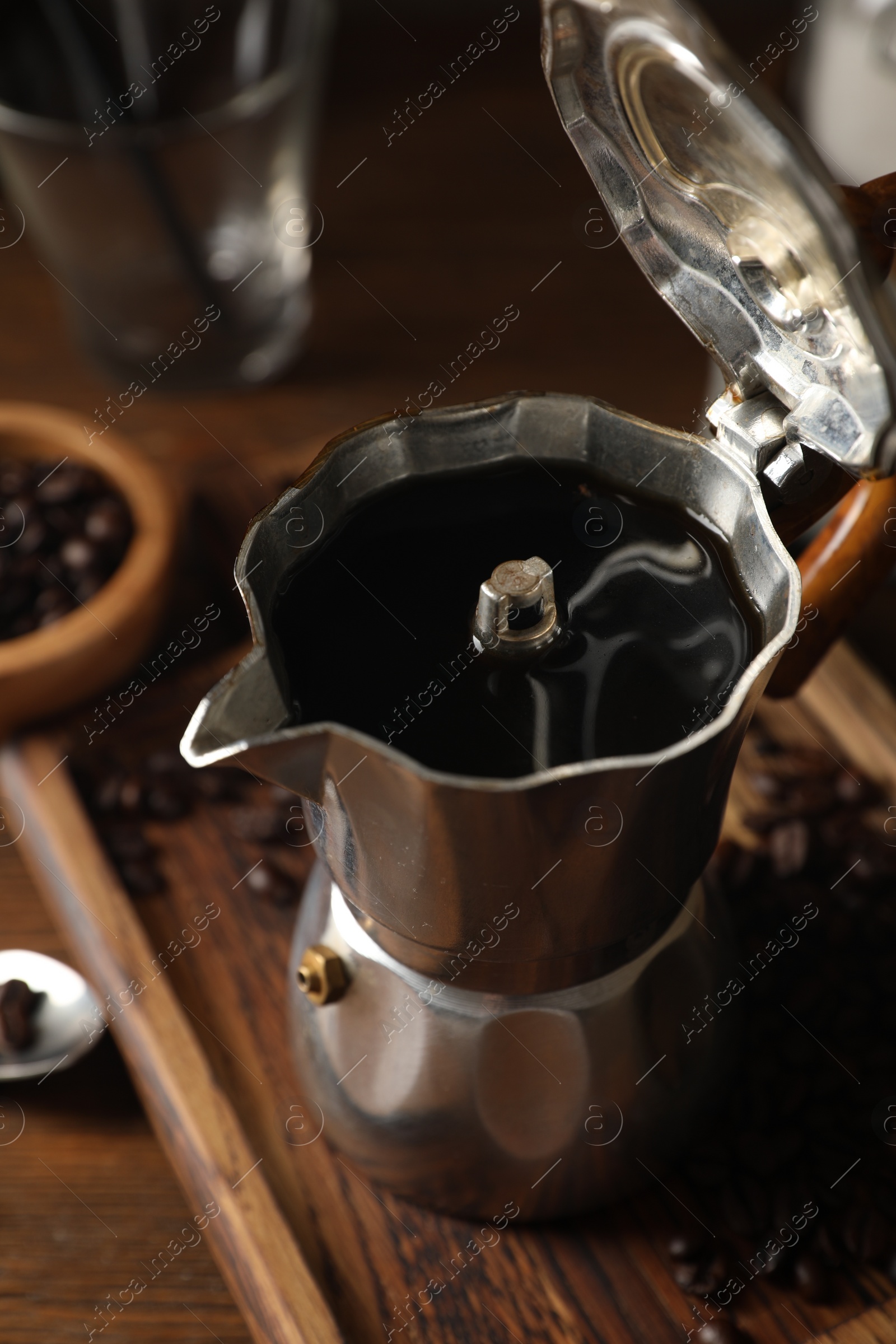 Photo of Brewed coffee in moka pot and beans on wooden table, closeup