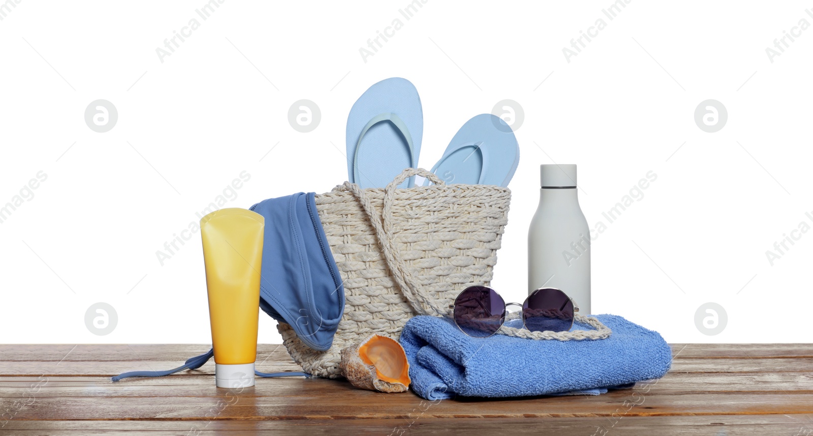 Photo of Stylish bag, sea shell and other beach accessories on wooden table against white background