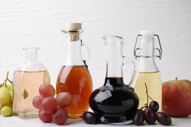 Photo of Different types of vinegar and ingredients on light tiled table, closeup