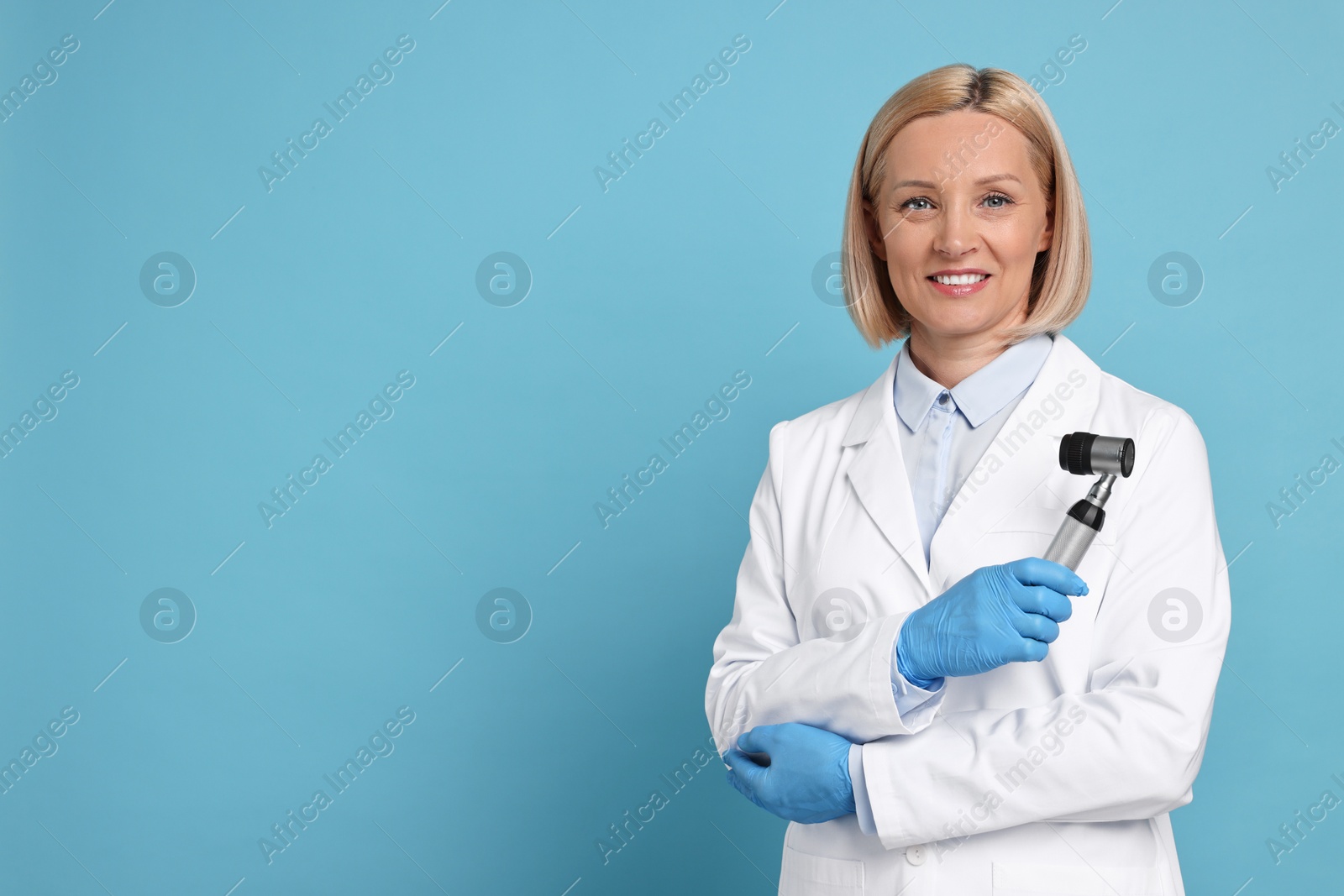 Photo of Happy dermatologist with dermatoscope on light blue background, space for text