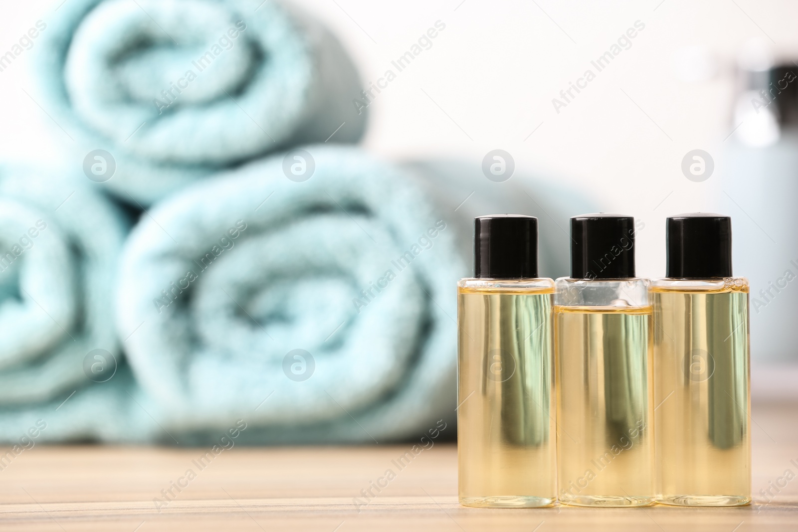 Photo of Mini bottles with cosmetic products and towels on table, space for text. Hotel amenities