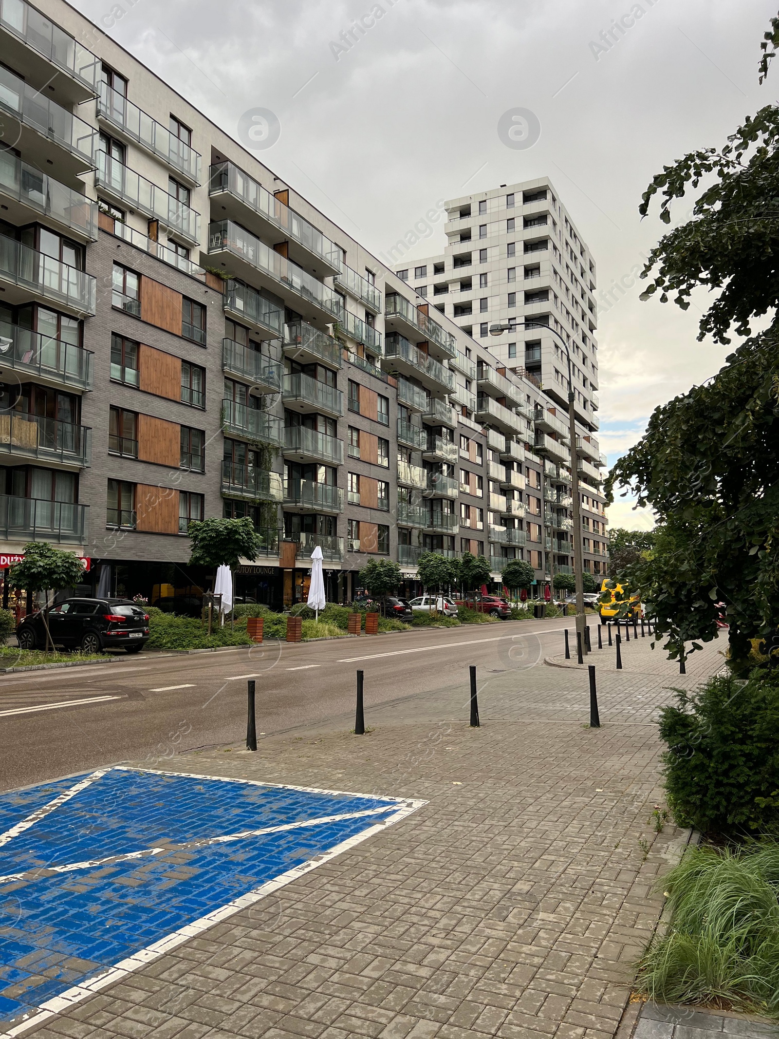 Photo of WARSAW, POLAND - JULY 11, 2022: Exterior of modern residential building with balconies and cars parked nearby