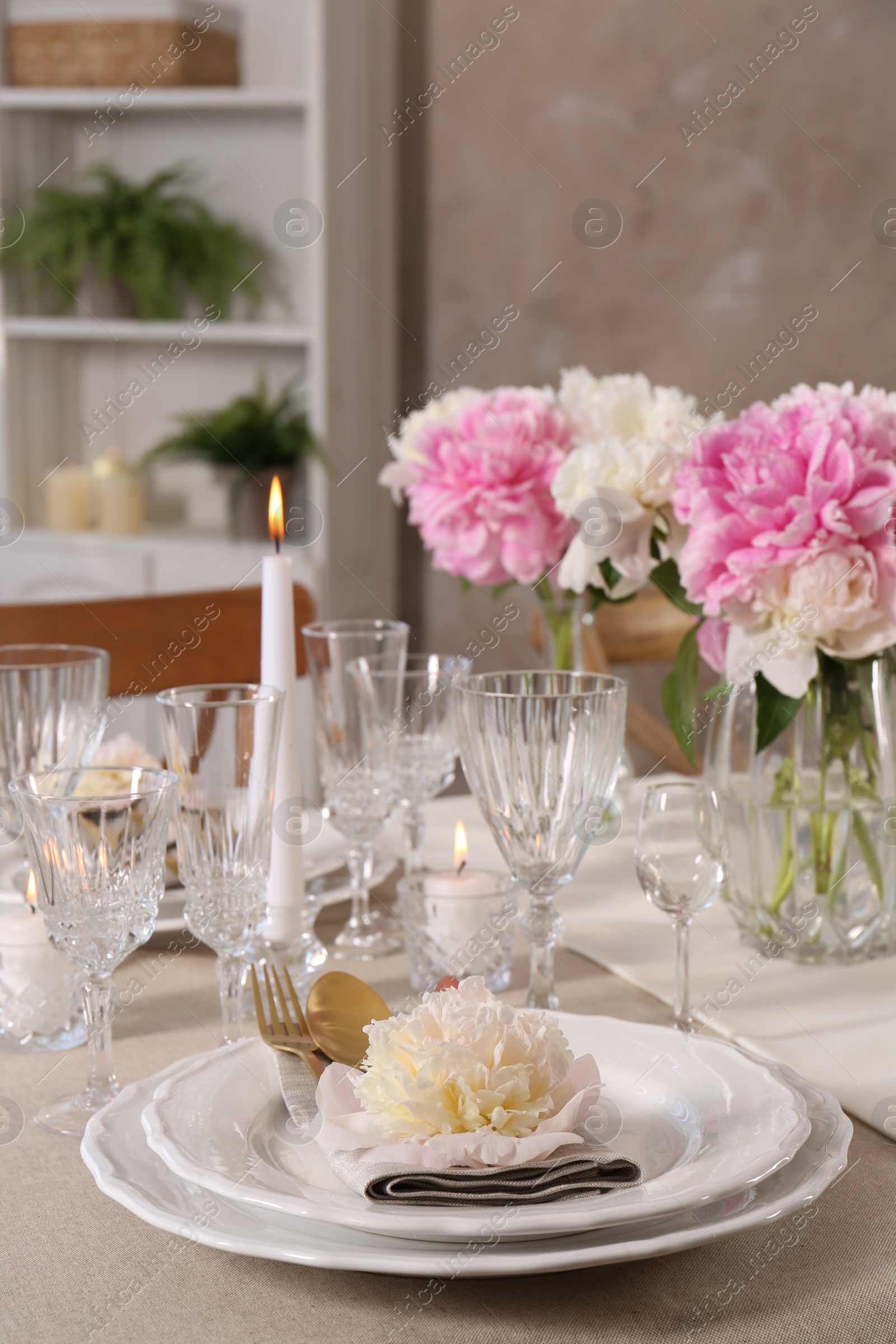 Photo of Stylish table setting with beautiful peonies and burning candles indoors