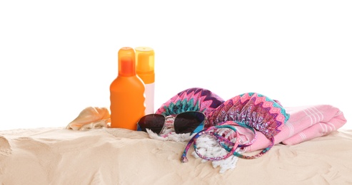 Different beach accessories on sand against white background