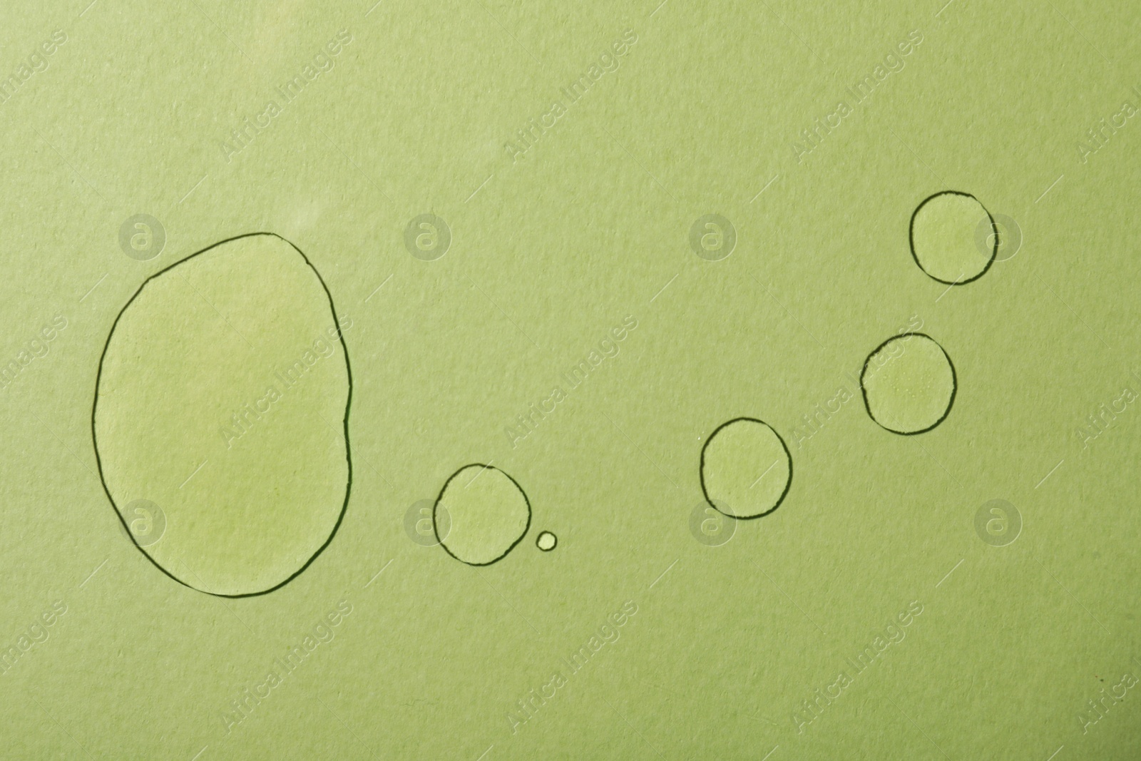 Photo of Drops of hydrophilic oil on light green background, flat lay