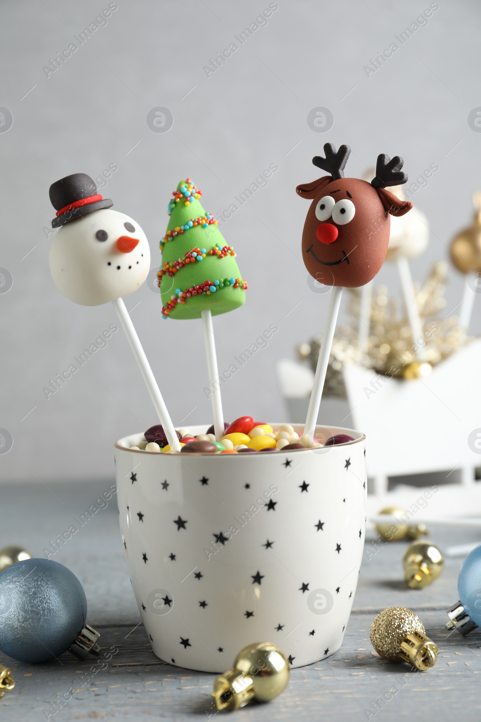 Photo of Delicious Christmas themed cake pops and festive decor on wooden table against grey background