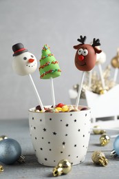 Delicious Christmas themed cake pops and festive decor on wooden table against grey background