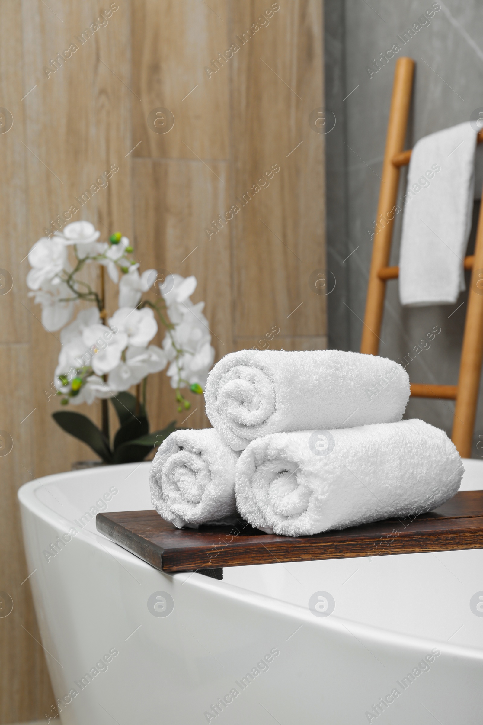 Photo of Rolled towels on tub tray in bathroom