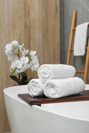 Photo of Rolled towels on tub tray in bathroom