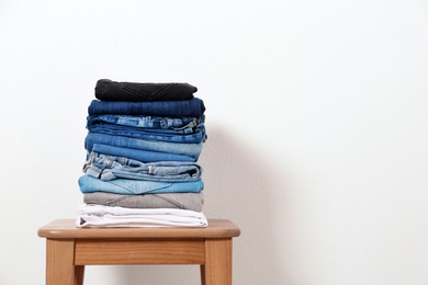 Photo of Stack of different jeans on table against white background. Space for text