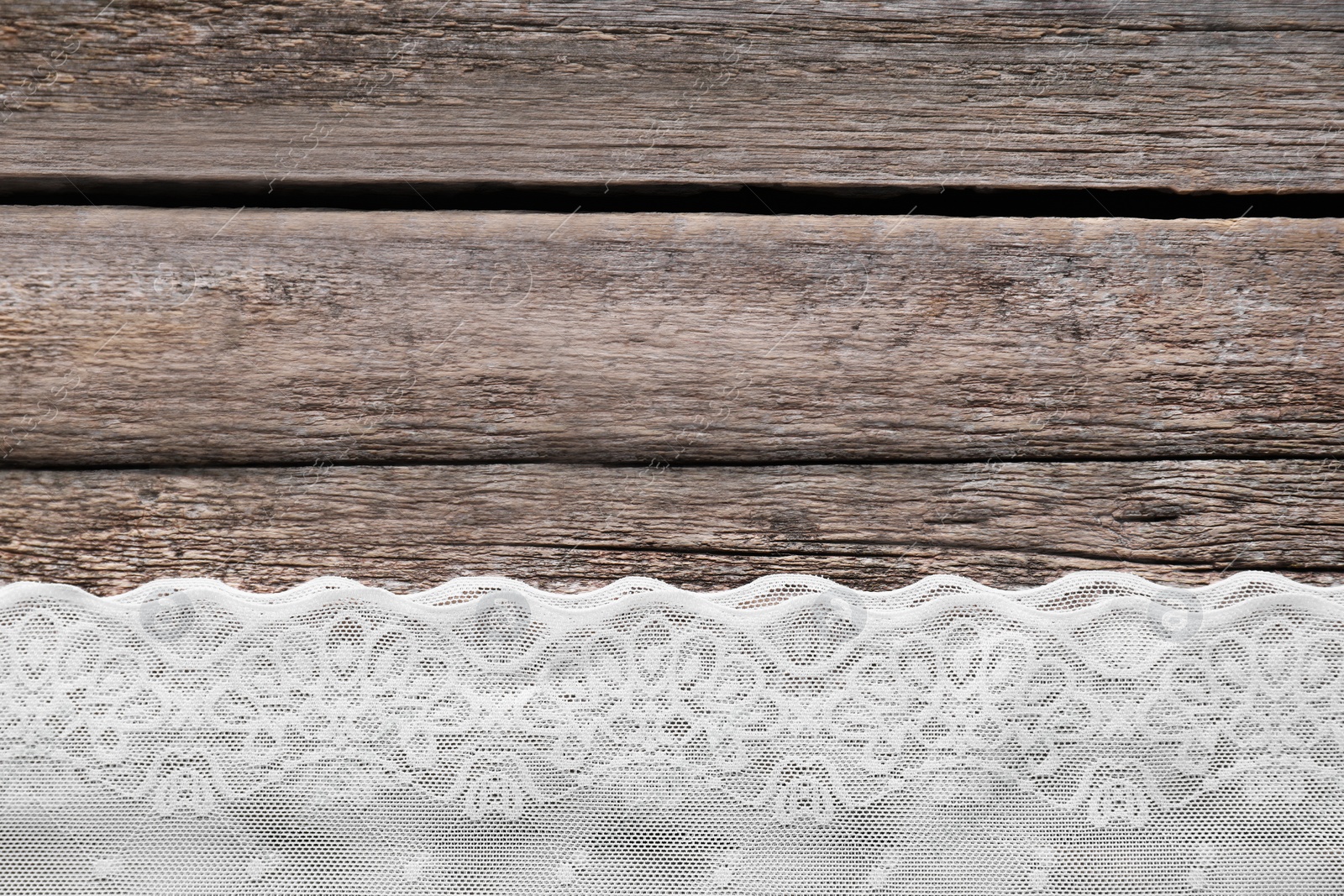 Photo of White lace on wooden table, top view. Space for text