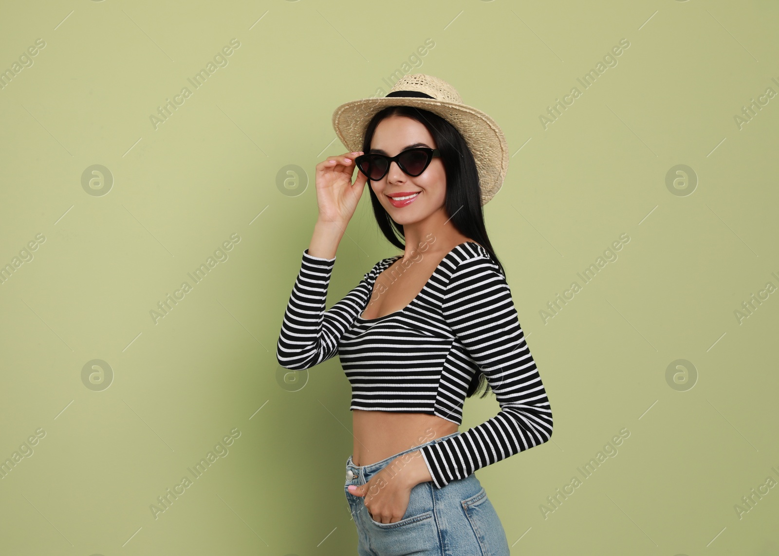 Photo of Beautiful young woman with straw hat and stylish sunglasses on light green background. Space for text
