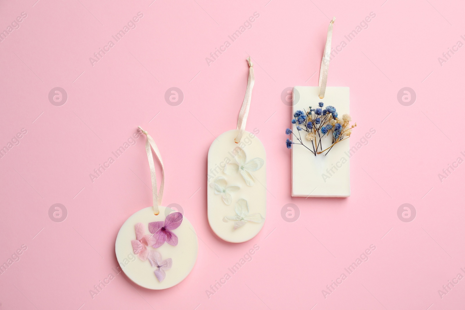 Photo of Beautiful scented sachets with flowers on pink background