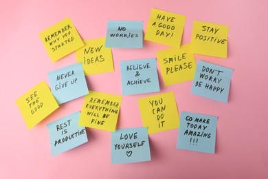 Paper notes with life-affirming phrases on pink background