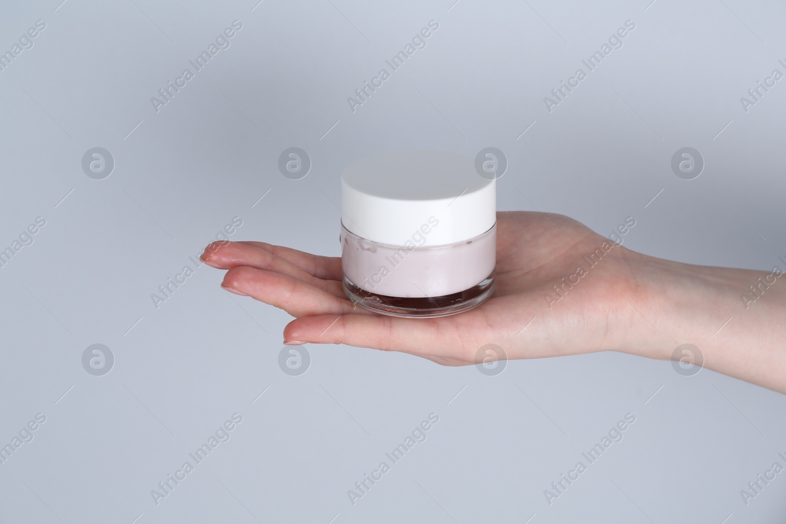 Photo of Woman holding jar of cream on grey background, closeup