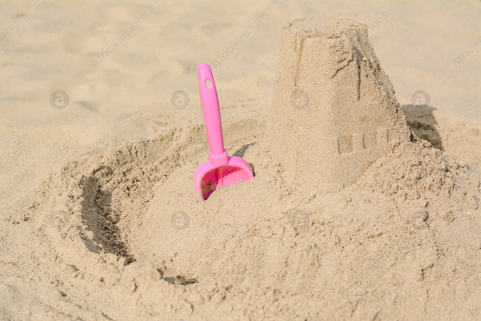 Photo of Beautiful sand castle and plastic toy on beach