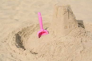 Photo of Beautiful sand castle and plastic toy on beach