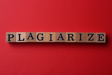Wooden cubes with word Plagiarism on red background, flat lay