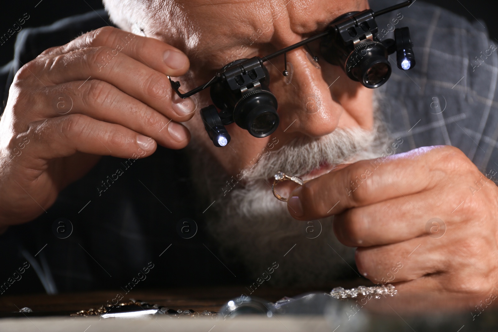 Photo of Male jeweler evaluating diamond ring in workshop, closeup view