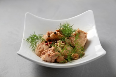 Plate with tasty canned cod liver on grey table