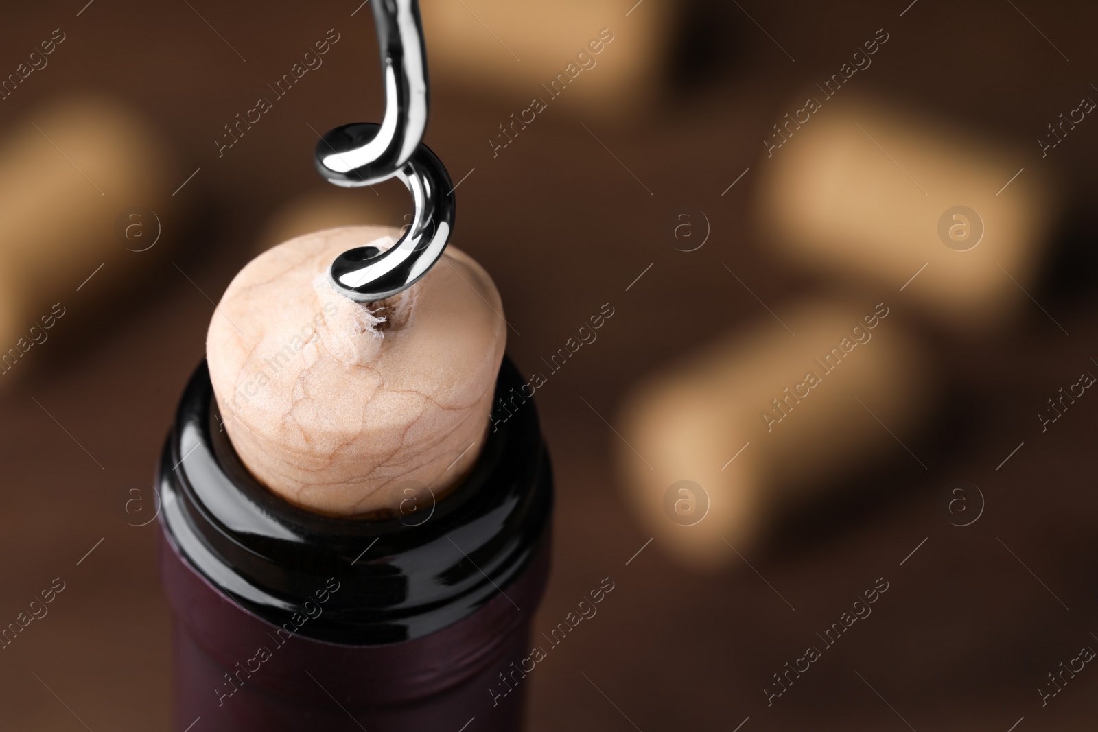 Photo of Opening wine bottle with corkscrew on wooden table, closeup. Space for text