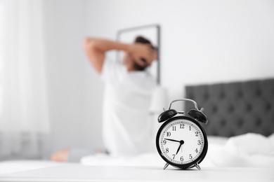 Analog alarm clock and blurred man on background. Time of day