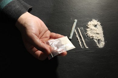 Photo of Drug addiction. Man with cocaine and rolled dollar banknote at grey textured table, top view
