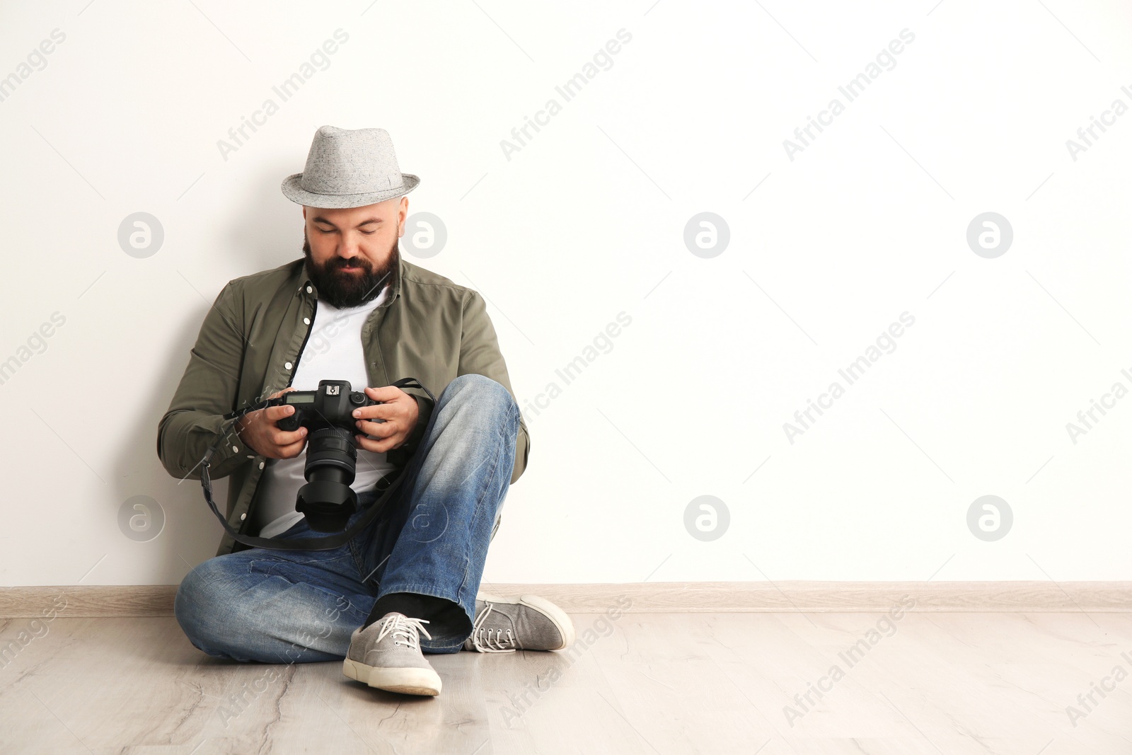 Photo of Male photographer with camera near light wall