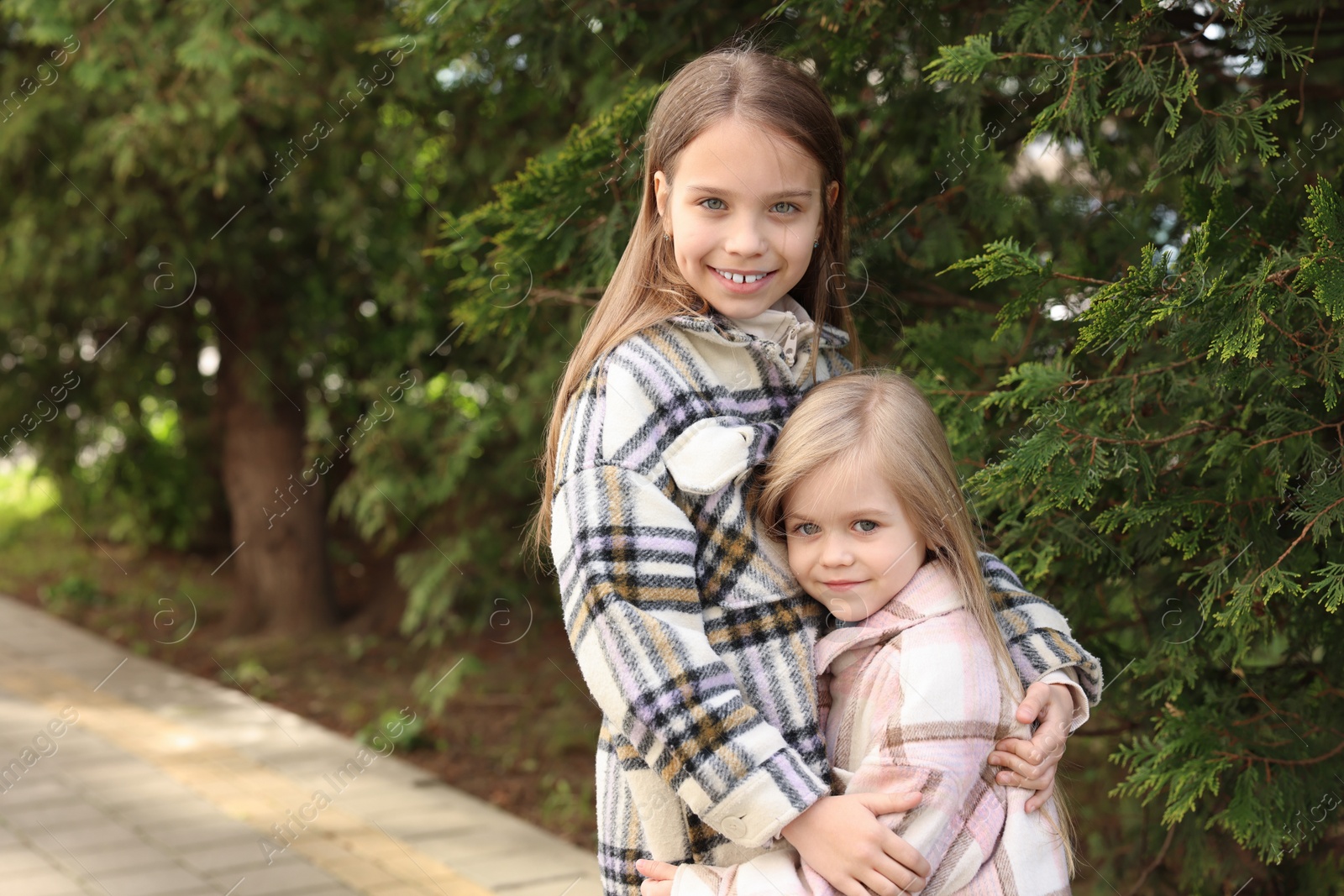 Photo of Cute little sisters spending time together outdoors, space for text