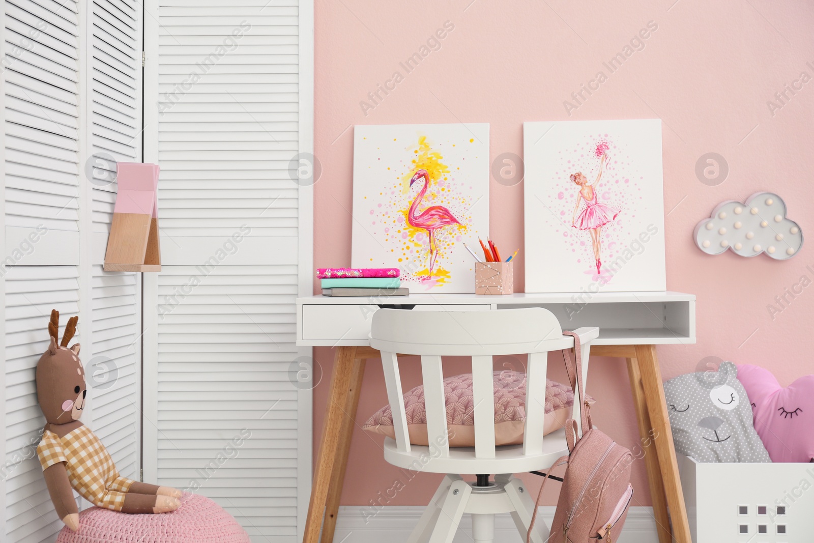 Photo of Stationery and pictures on white table in children's room. Interior design