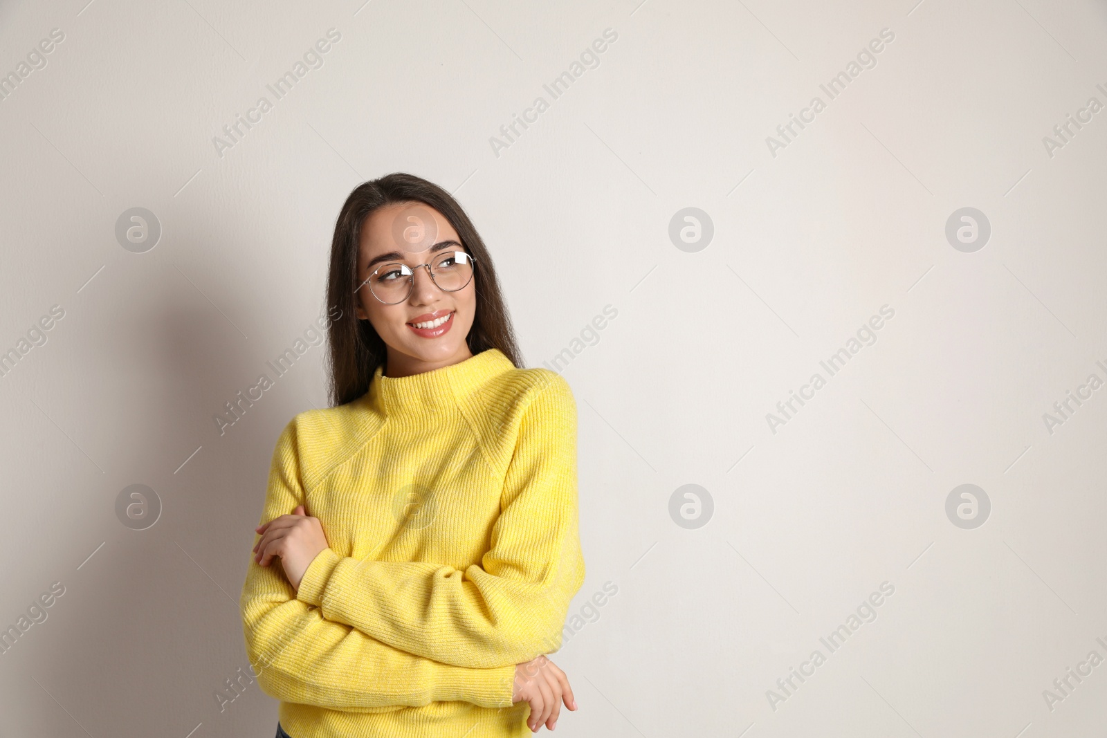 Photo of Beautiful young woman wearing yellow warm sweater on white background. Space for text