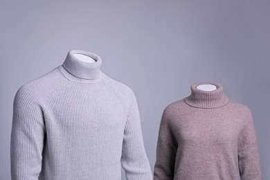 Photo of Male and female mannequins dressed in stylish sweaters on grey background