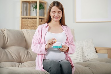 Beautiful pregnant woman holding pill at home
