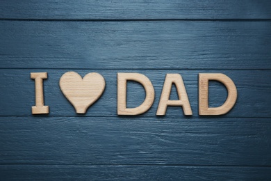 Photo of Phrase I LOVE DAD made of letters on wooden background, top view