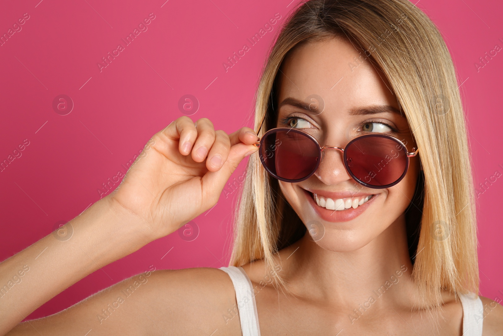 Photo of Beautiful woman in stylish sunglasses on pink background, closeup