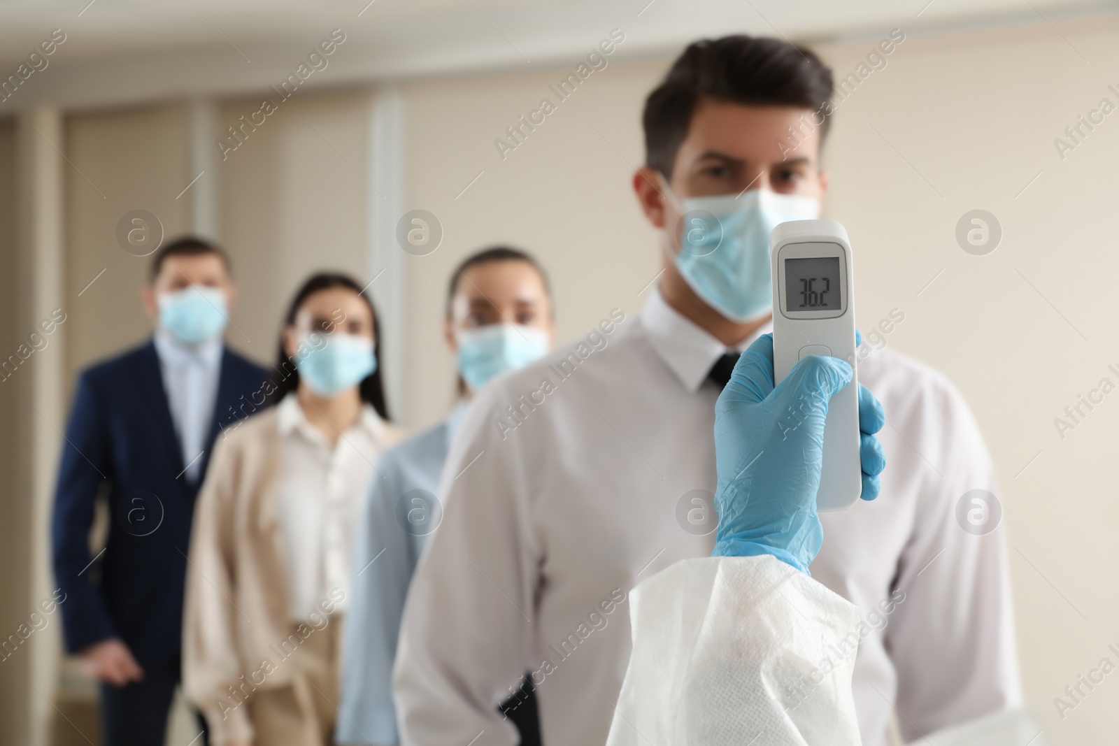 Photo of Doctor measuring employees temperature in office, closeup. Prevent spreading of Covid-19