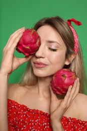 Photo of Young woman with fresh pitahayas on green background. Exotic fruits