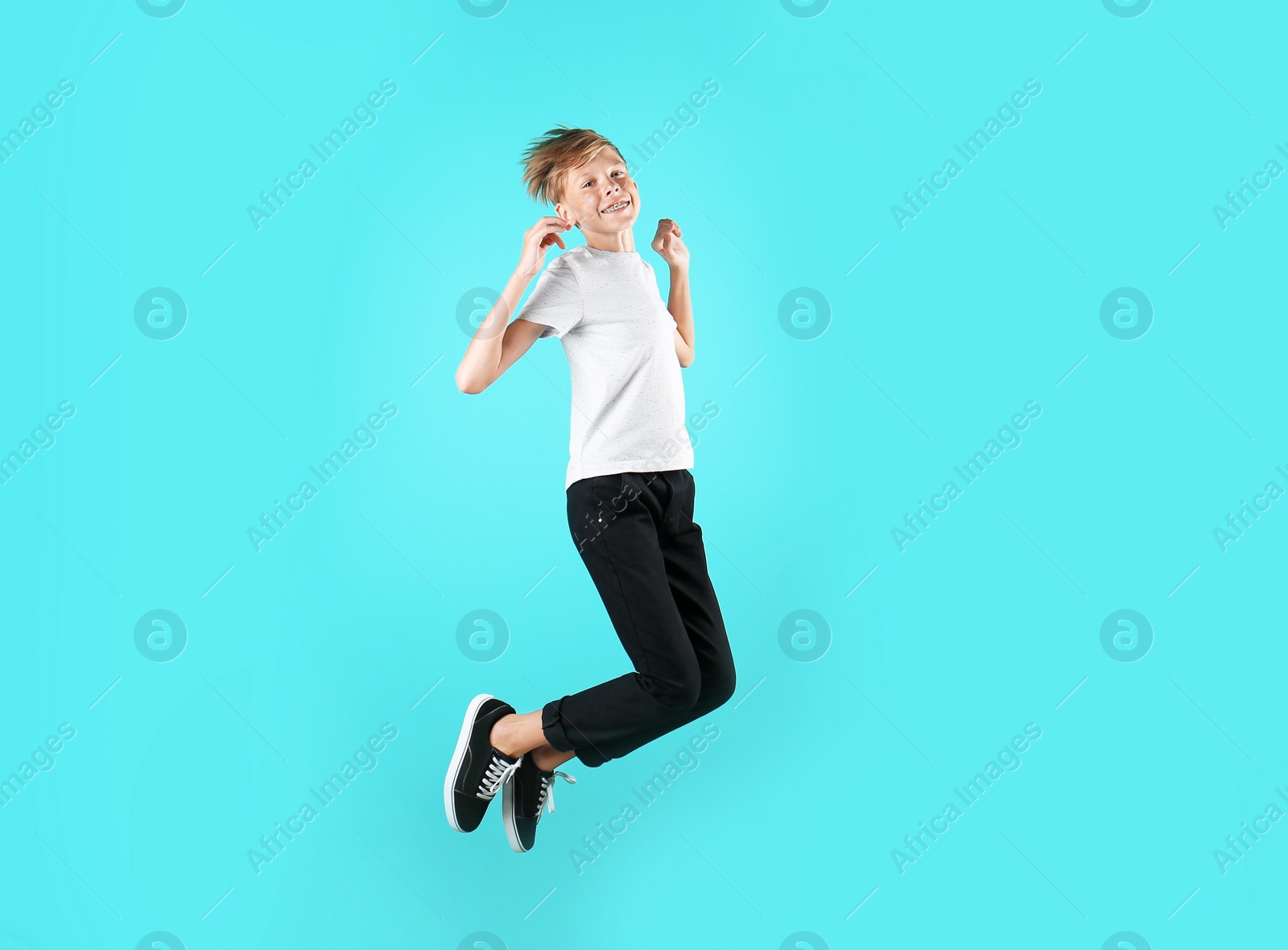 Photo of Portrait of young boy jumping on color background