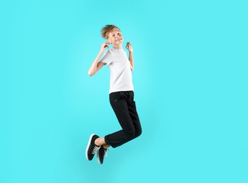 Portrait of young boy jumping on color background