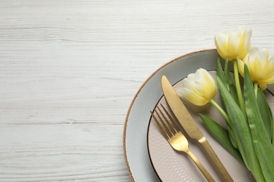 Photo of Stylish table setting with cutlery and tulips on white wooden background, top view. Space for text
