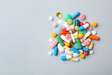 Photo of Heap of different pills on grey background, top view. Space for text