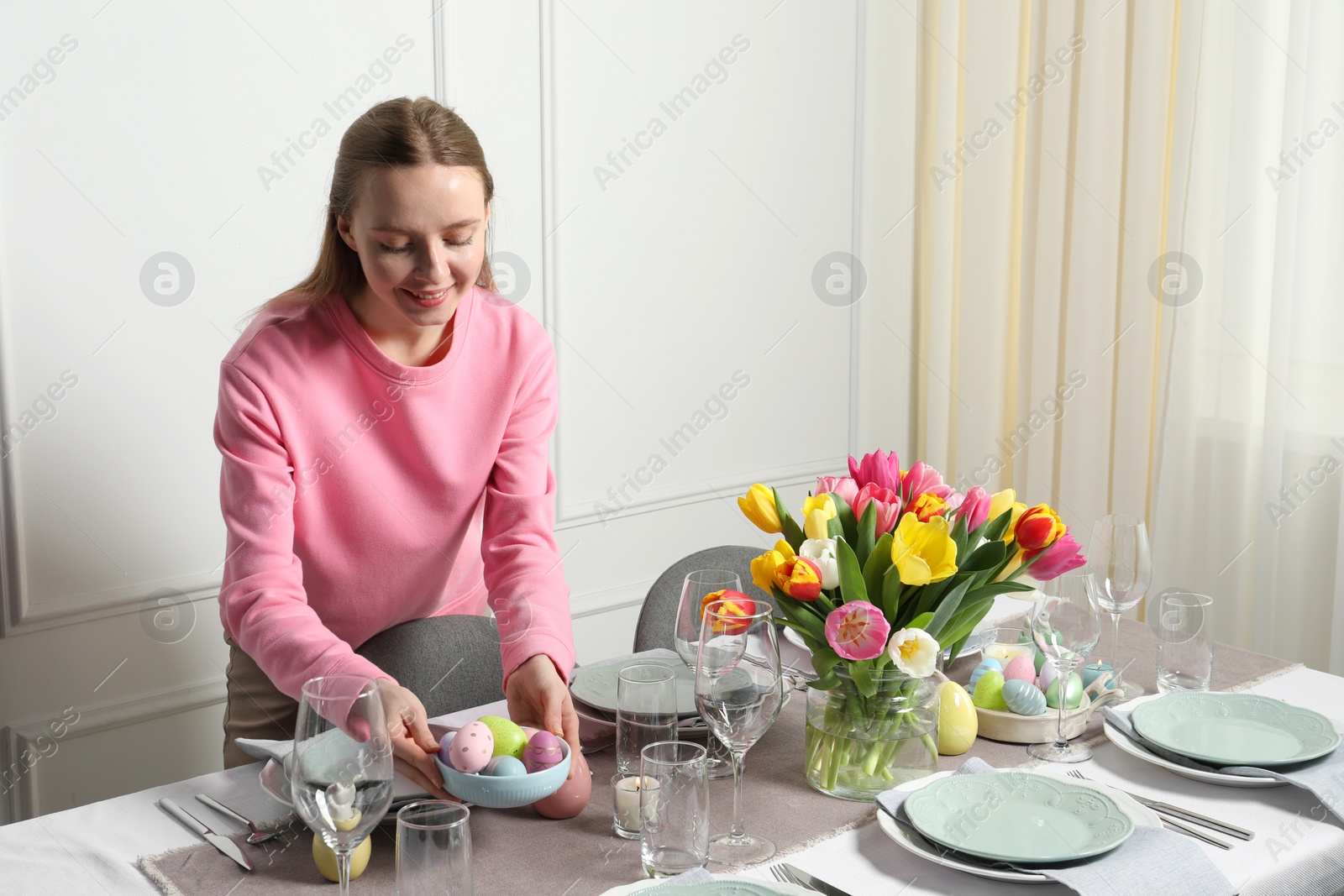 Photo of Woman setting table for festive Easter dinner at home