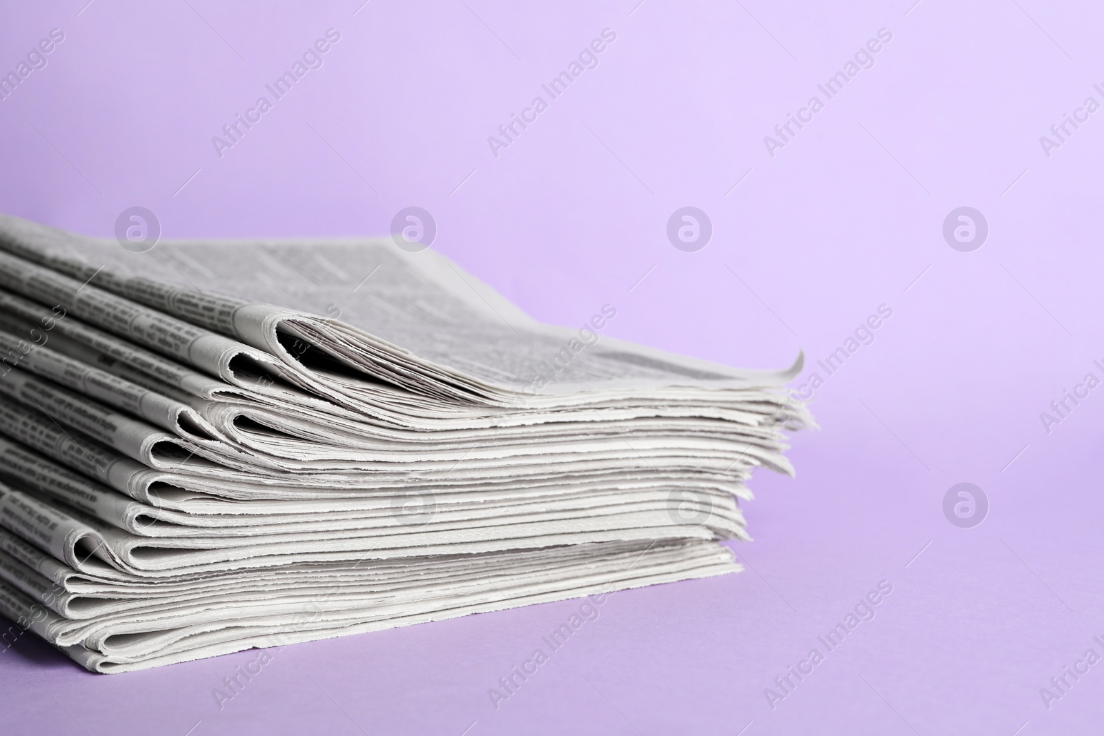 Photo of Stack of newspapers on light violet background. Journalist's work