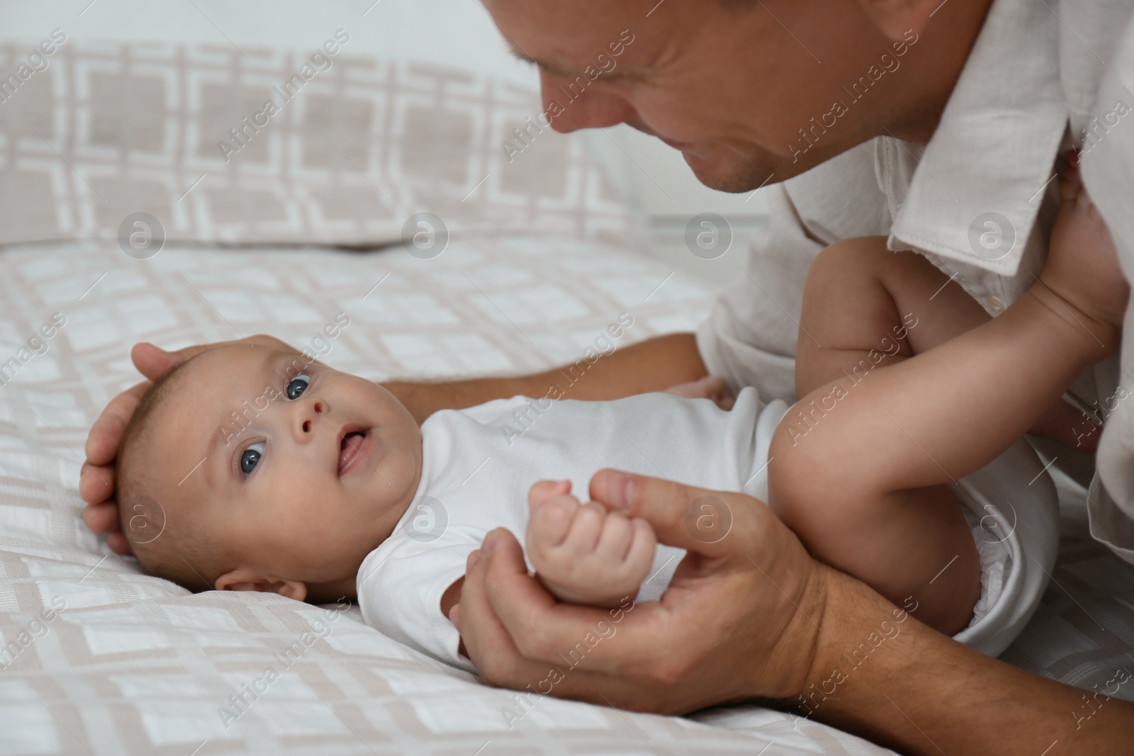 Photo of Happy father with his cute baby on bed