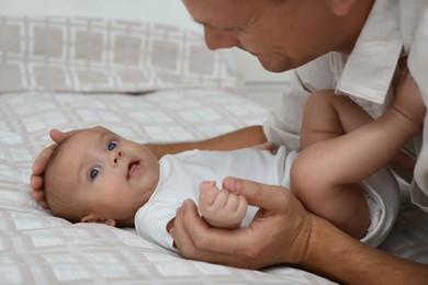 Happy father with his cute baby on bed