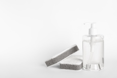 Bottle of detergent and sponges on white background