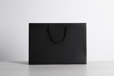 Black paper bag on white wooden table