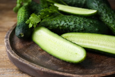 Photo of Fresh ripe cucumbers and parsley on wooden table, closeup