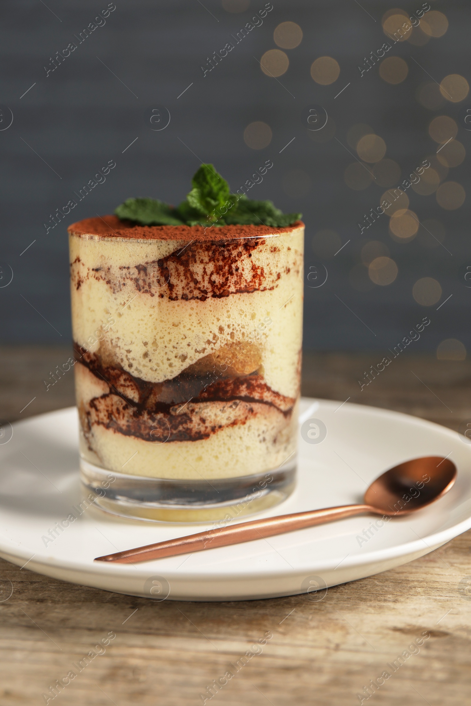 Photo of Tasty tiramisu and mint in glass on wooden table, closeup