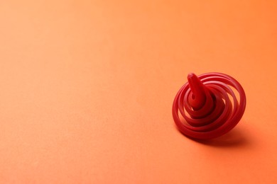Photo of One red spinning top on orange background, closeup. Space for text